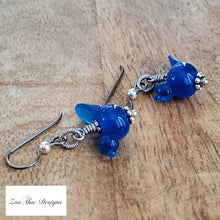 Load image into Gallery viewer, Blue Bird Earrings on wooden background..
