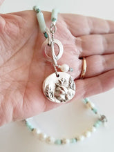 Load image into Gallery viewer, Amazonite and Pearl Necklace with Bird Pendant held in hand.
