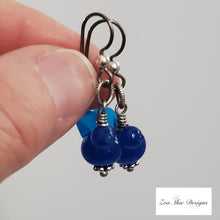Load image into Gallery viewer, Blue Bird Earrings held by thumb.
