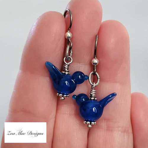 Blue Bird Earrings held in hand.