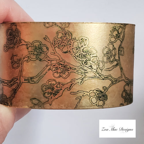 Cherry Blossom Etched Brass Cuff held in hand.