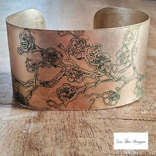 Load image into Gallery viewer, Cherry Blossom Etched Brass Cuff on wooden background.

