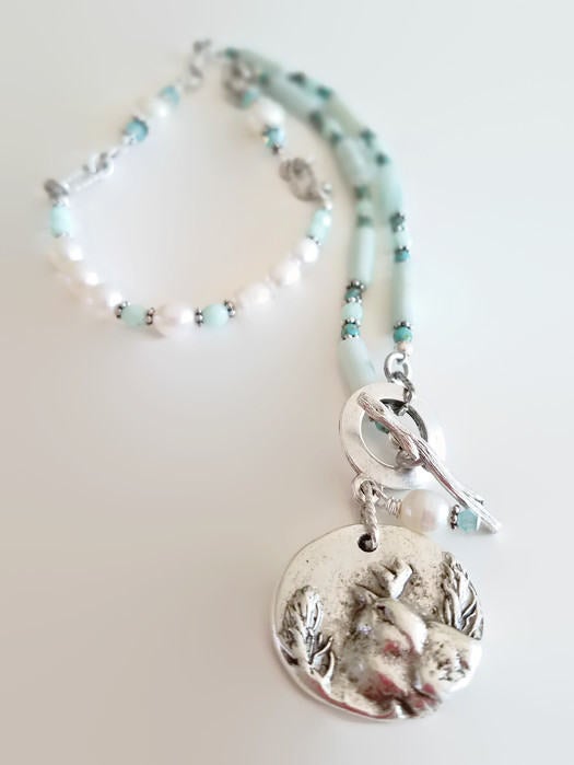 Amazonite and Pearl Necklace with Bird Pendant on white background.