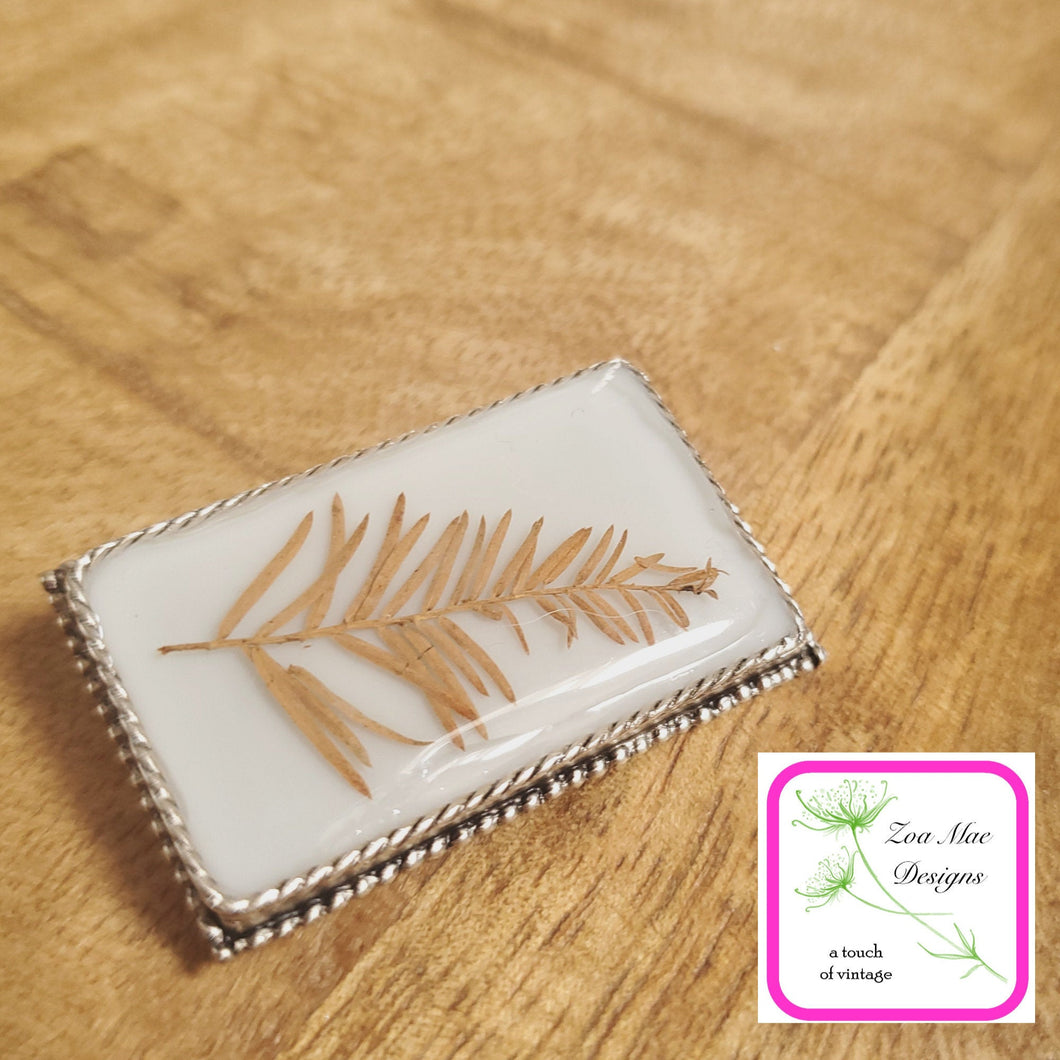 Pine Leaf on Grey Convertible Brooch Pin on wooden background.