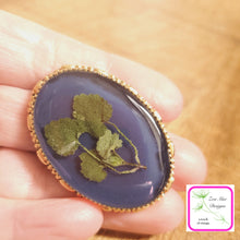 Load image into Gallery viewer,  Navy with Leaves Convertible Brooch Pin held in hand.
