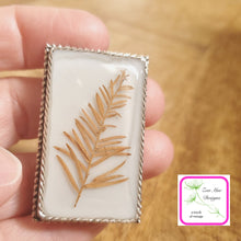 Load image into Gallery viewer, Pine Leaf on Grey Convertible Brooch Pin held in hand.
