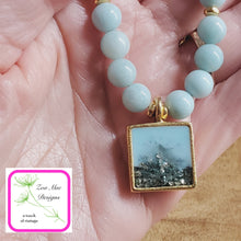Load image into Gallery viewer, Antique Gold Gemstone and Glitter Necklace held in hand.
