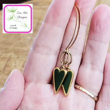 Load image into Gallery viewer, Antique Gold dangle heart earrings held in hand.
